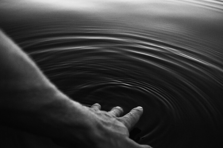 Hand berührt Wasseroberfläche